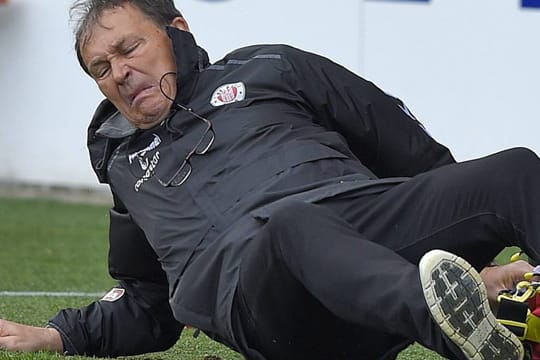 Unsanfte Landung: Pauli-Coach Ewald Lienen stürzt bei dem Versuch, einen ins Seitenaus rollenden Ball zu stoppen.