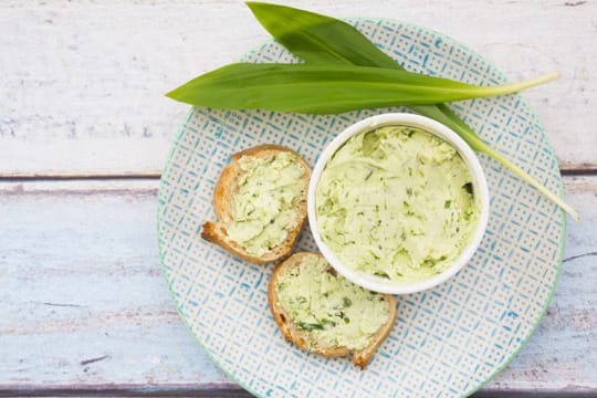 Kräuterbutter in Schale mit zwei Brotscheiben: Selbstgemachte Bärlauchbutter ist ein echter Gaumenschmaus.