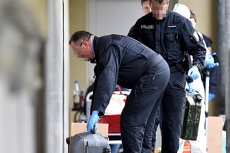 Sprengstoffexperten tragen Taschen und Koffer mit sichergestellten Gegenständen aus der Täterwohnung in Oberursel.