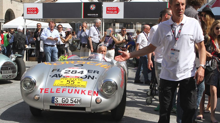 Der sogenannte Knickscheibe Porsches 550 Spyder, der schon im Jahr 1954 die 1000 Meilen von Brescia nach Rom und zurück um den Sieg fuhr. Seinerzeit von Hans Herrmann pilotiert, der mit seinem wagemutigen Stunt in die Geschichtsbücher einging: Er ließ den 550 noch unter einer sich absenkenden Bahnschranke hindurch schlüpfen. In diesem Jahr lenkt Porsche-Chef Mathias Müller den 550 Spyder.