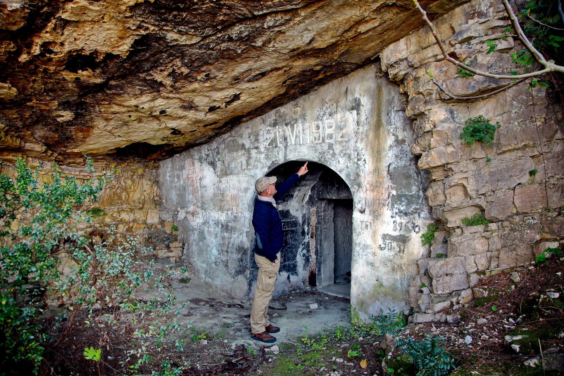 Ein Mitarbeiter der albanischen Küstenbehörde zeigt den Eingang zu einem Schutztunnel. Auch für die Röhren, die sich durch die Insel ziehen, gibt es neue Nutzungsideen - etwa als Weinkeller.