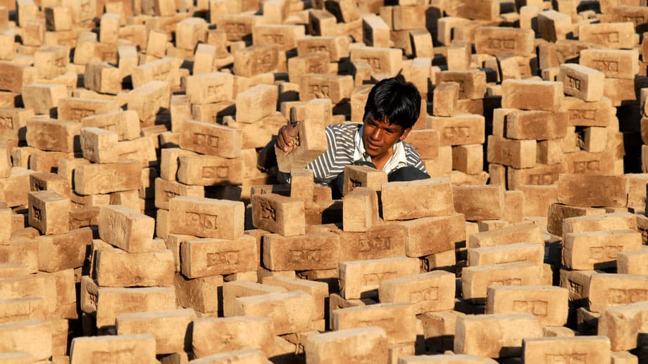 Ziegelsteine in der sengenden Sonne aufschichten - auch das ist eine typische Arbeit für indische Kinder.