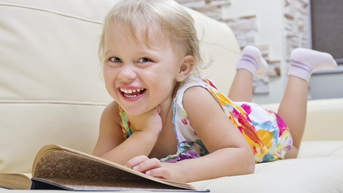 Ein Mädchen im Vorschulalter schmökert in einem Buch.