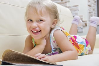 Ein Mädchen im Vorschulalter schmökert in einem Buch.