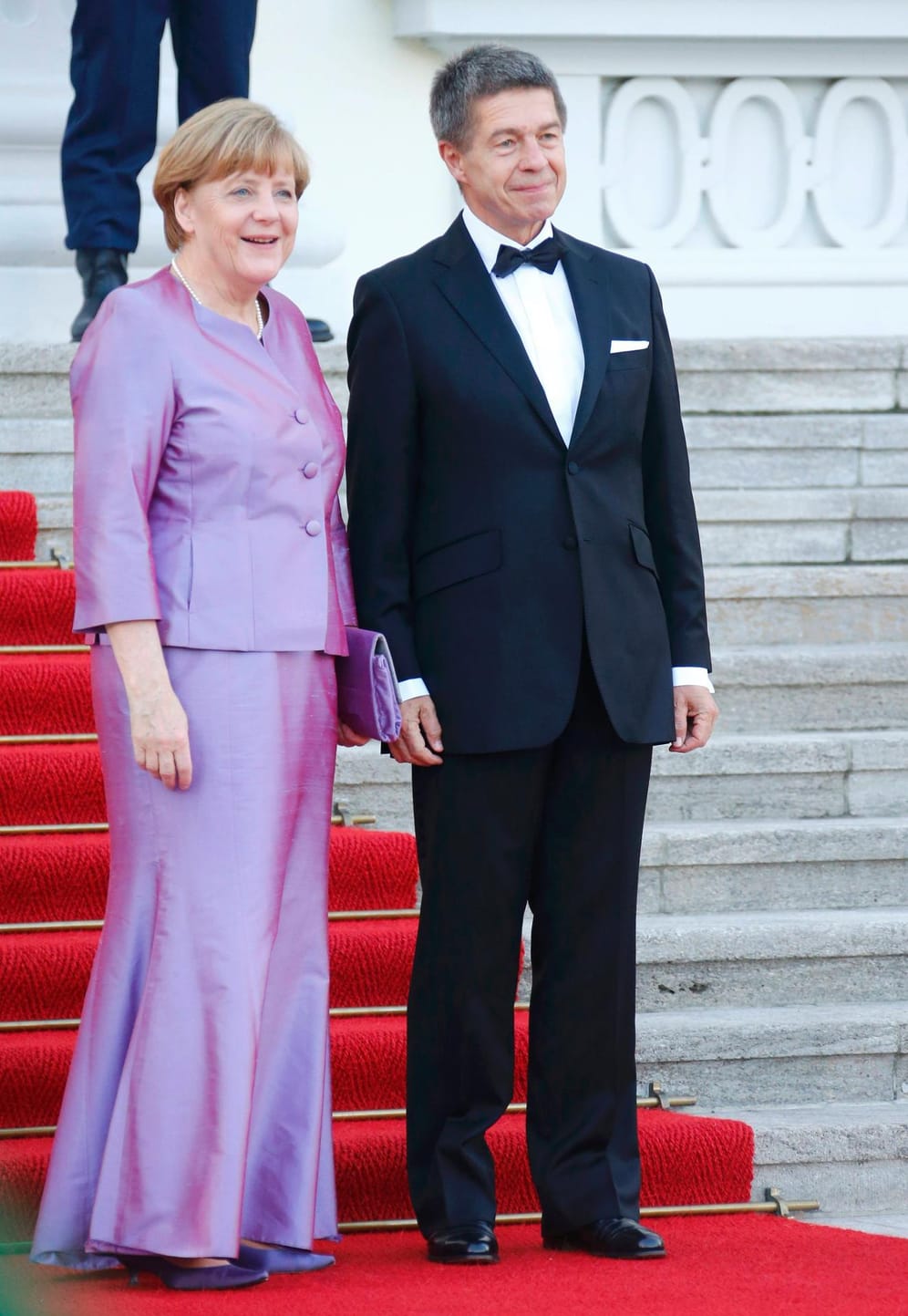 Bundeskanzlerin Angela Merkel kommt in lila changierender Robe. An ihrer Seite: Ehemann Joachim Sauer.