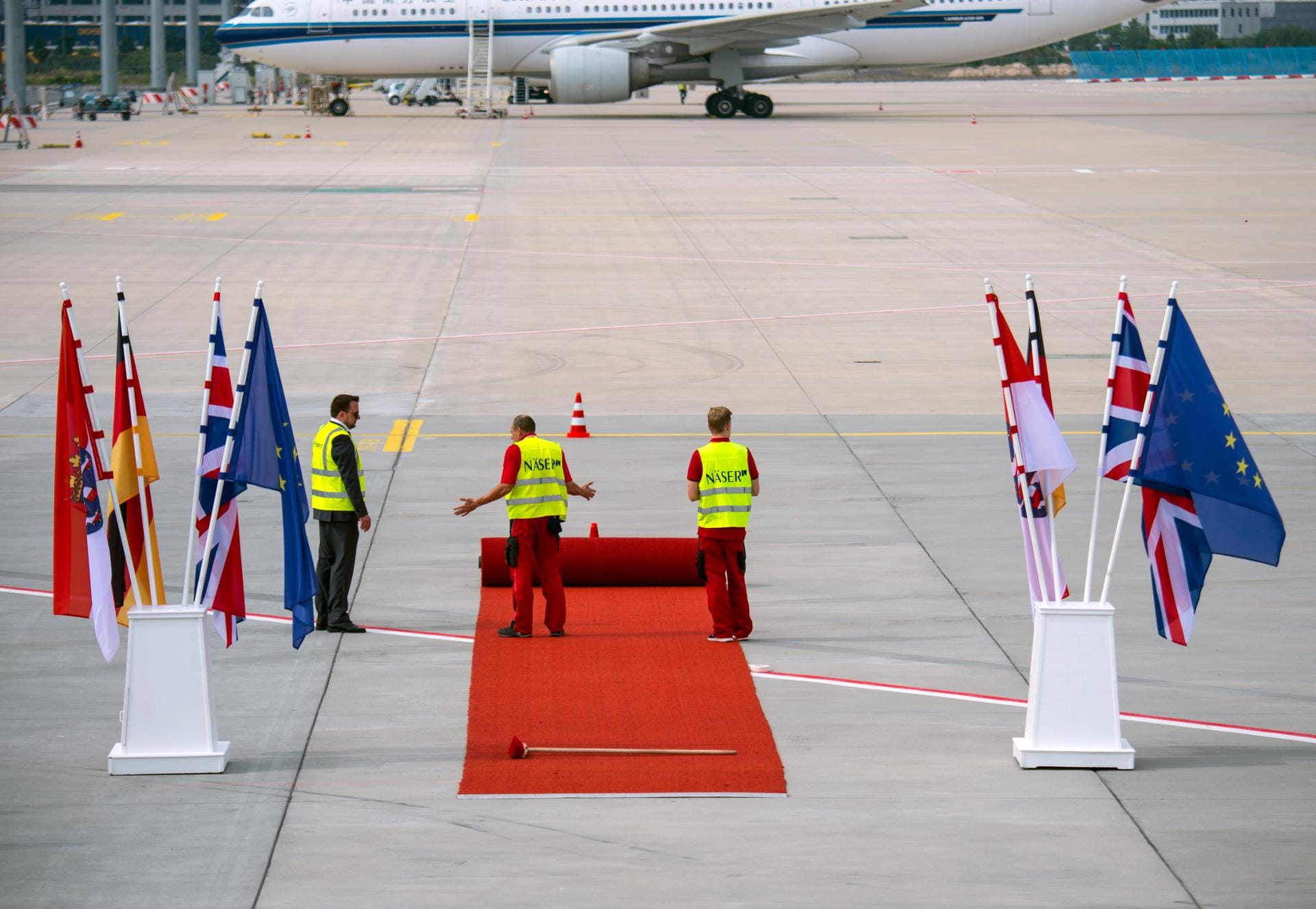 Mitarbeiter des Frankfurter Flughafens rollen für die Ankunft der Königin einen roten Teppich aus.