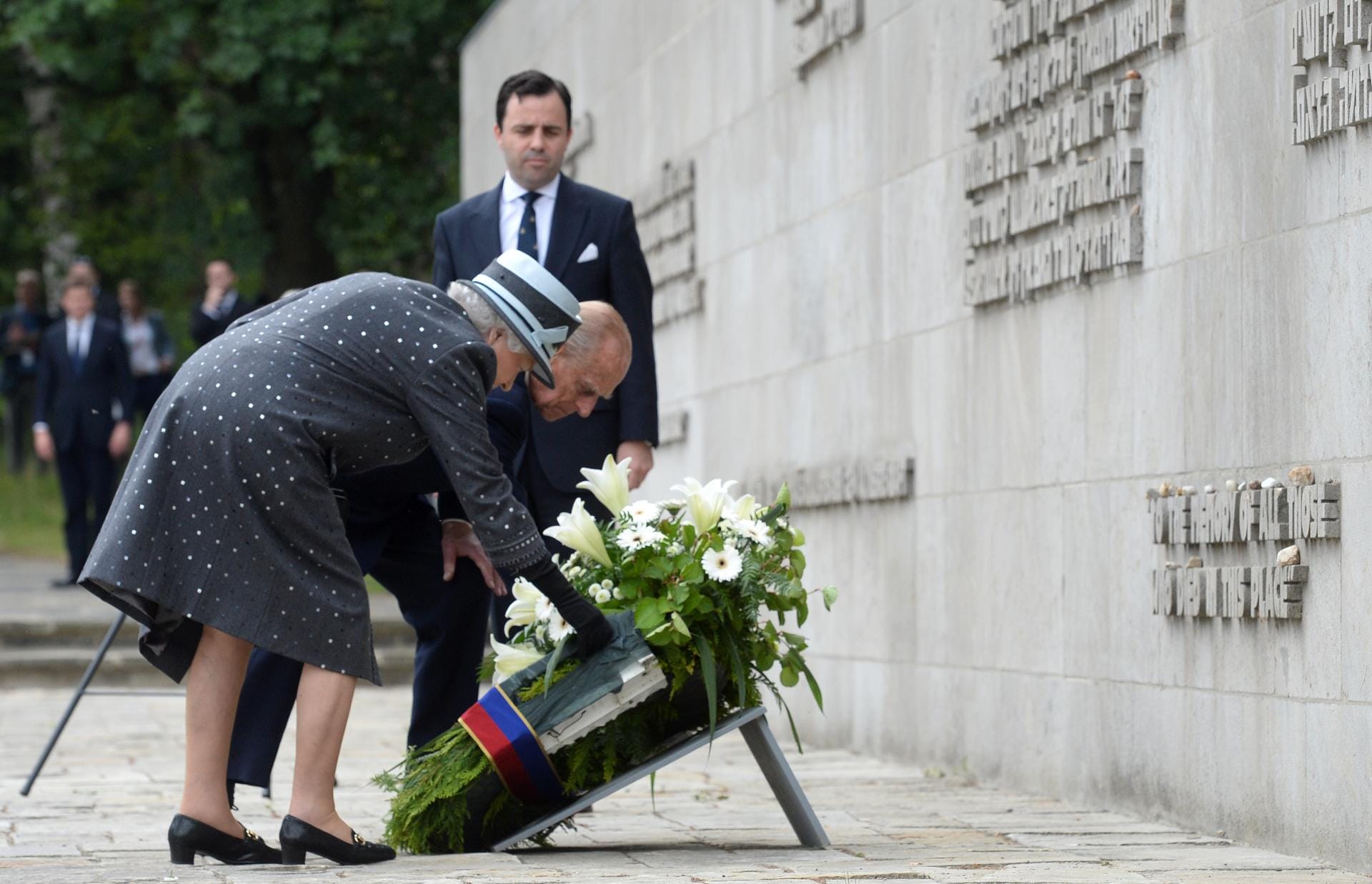 Elizabeth II. und Prinz Philip legenan der Inschriftenwand einen Kranz nieder.