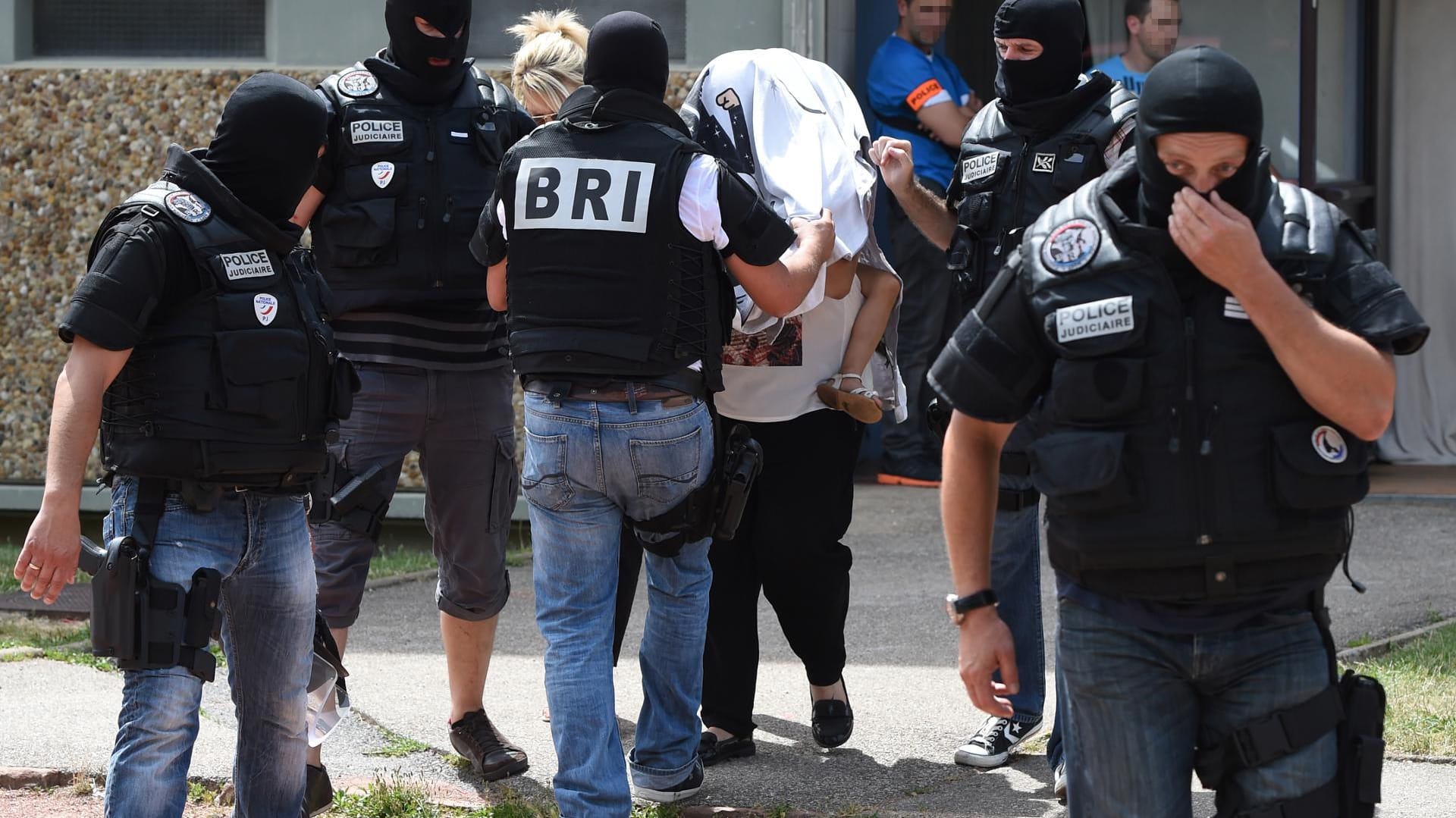 Eine Spezialeinheit eskortiert die Frau und Tochter des Täters aus einem Gebäude.