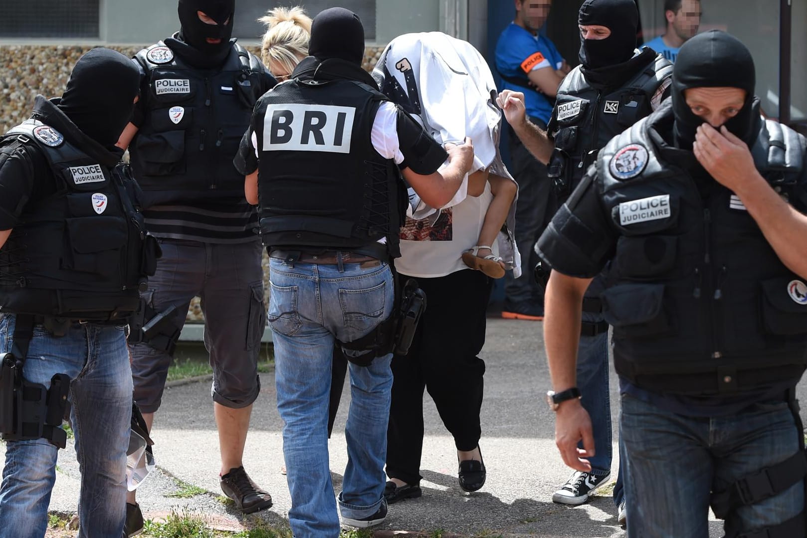 Eine Spezialeinheit eskortiert die Frau und Tochter des Täters aus einem Gebäude.