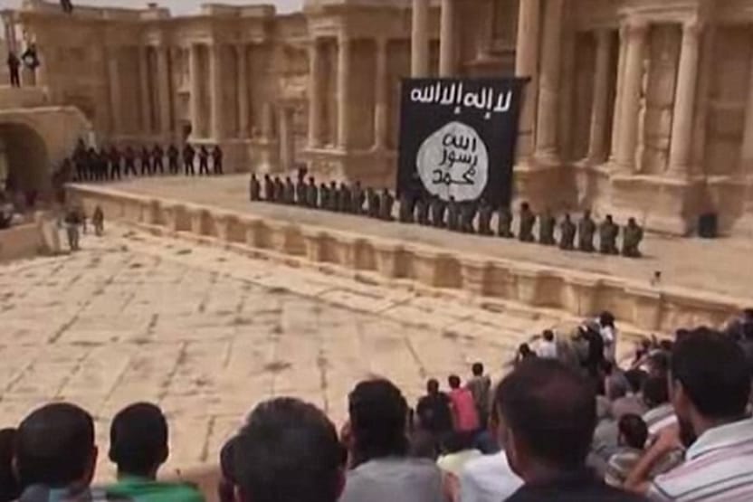 Screenshot aus dem Hinrichtungsvideo aus Palmyra: Die Delinquenten knien vor der übergroßen IS-Flagge.