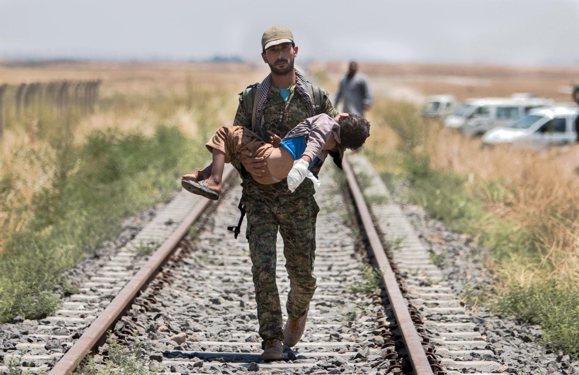 A Kurdish People's Protection Units fighter carries an injured boy as they make their way towards the Turkish border in Tel Abyad town A Kurdish People's Protection Units fighter carries an injured boy as they make their way towards the Turkish border in Tel Abyad town