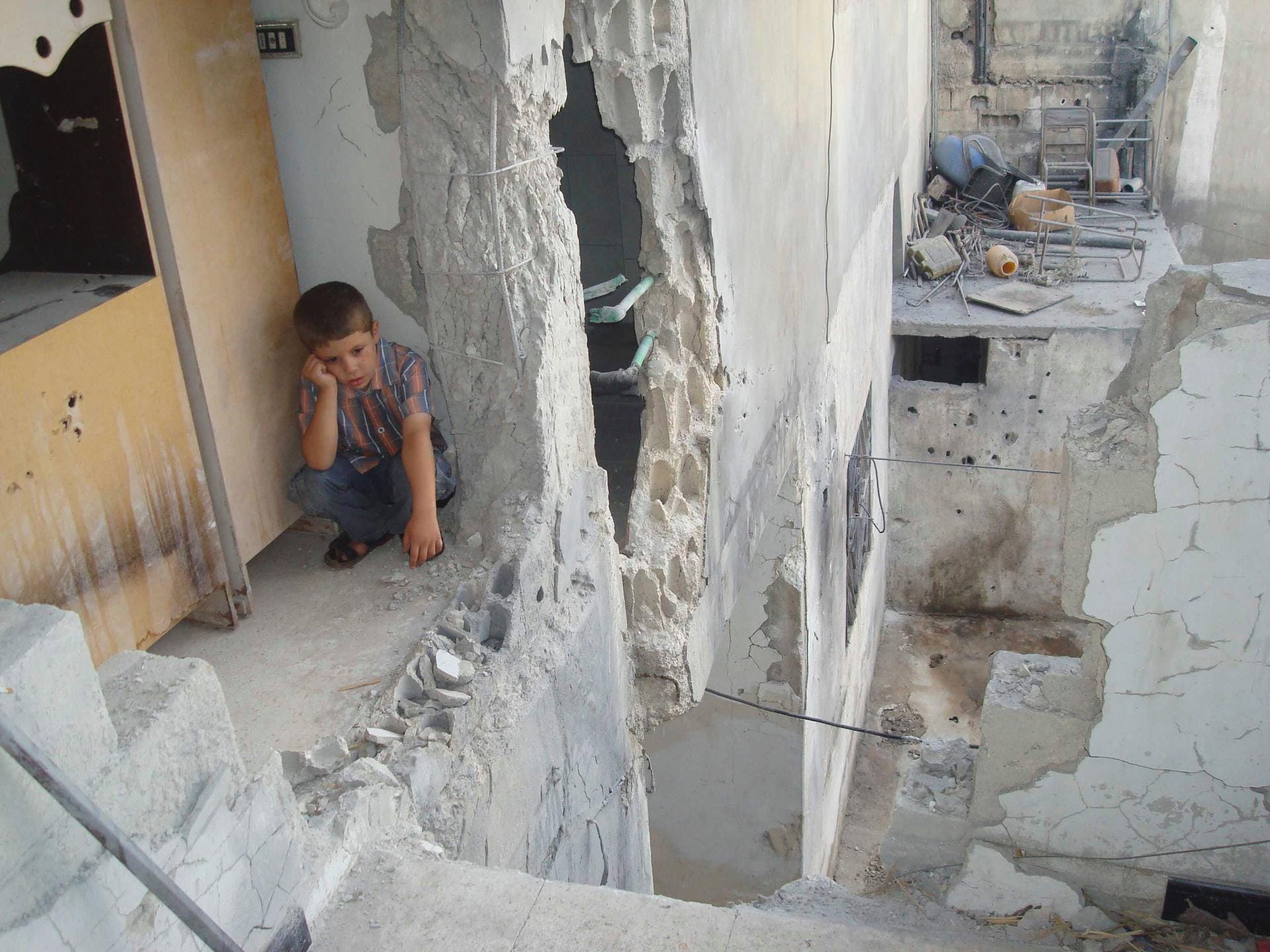 Ein Kind sitzt in den Ruinen seines Elternhauses in Homs: Eine ganze Generation wächst traumatisiert auf. Ein Kind sitzt in den Ruinen seines Elternhauses in Homs: Eine ganze Generation wächst traumatisiert auf.