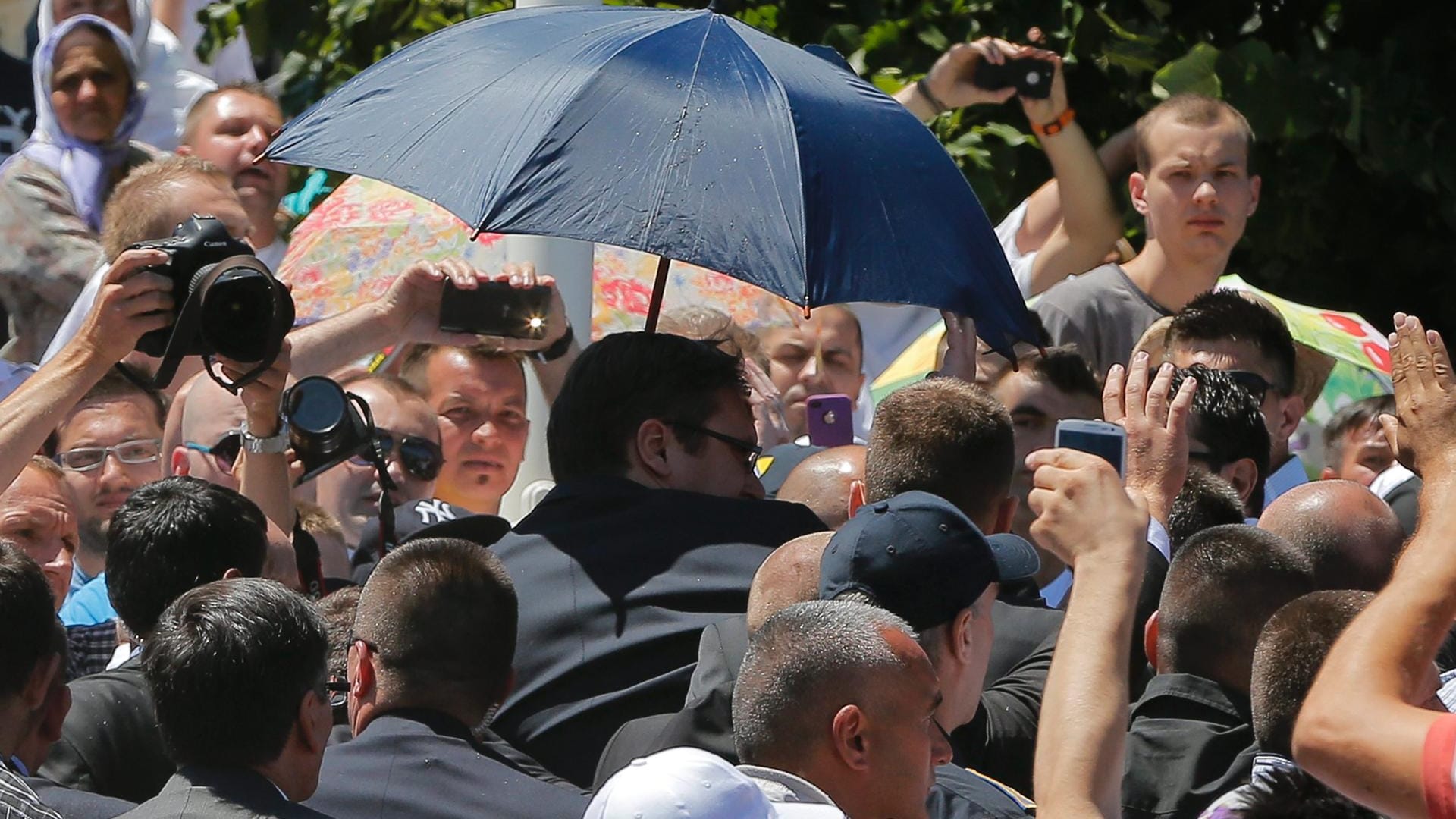 Ministerpräsident Aleksandar Vucic (unter dem Schirm) flieht von der Gedenkfeier zum Srebrenica-Massaker. Ministerpräsident Aleksandar Vucic (unter dem Schirm) flieht von der Gedenkfeier zum Srebrenica-Massaker.