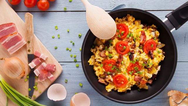 Herzhaftes Frühstück: Rührei mit Speck, frischen Tomaten und Kräutern passt in das Konzept der Paleo-Diät.