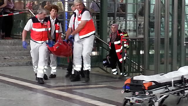 Sanitäter transportieren den angeschossenen Mann aus dem Bahnhof