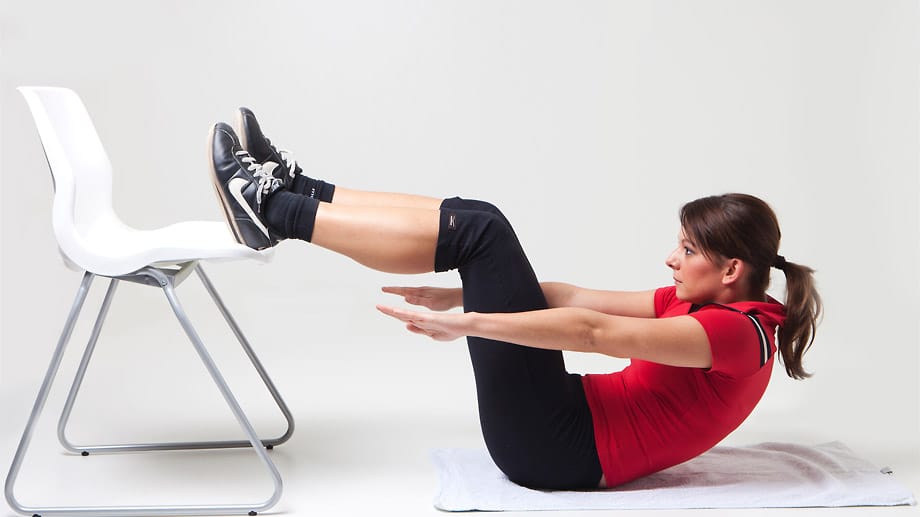 Steigerung muss sein: Wer mit den Crunches am Boden trainiert hat, steigert die Intensität der Übung einfach mit einem Stuhl. Die permanente Steigerung der Körperspannung ist wichtig, um die Bauchmuskeln auszuprägen.