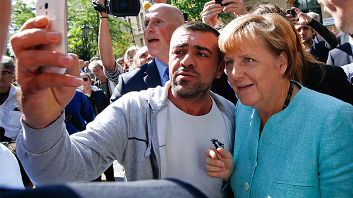 Angela Merkel posiert für Selfies mit Flüchtlingen, aber ihre großzügig ausgesprochene Einreiseerlaubnis sorgt zunehmend für Unmut.