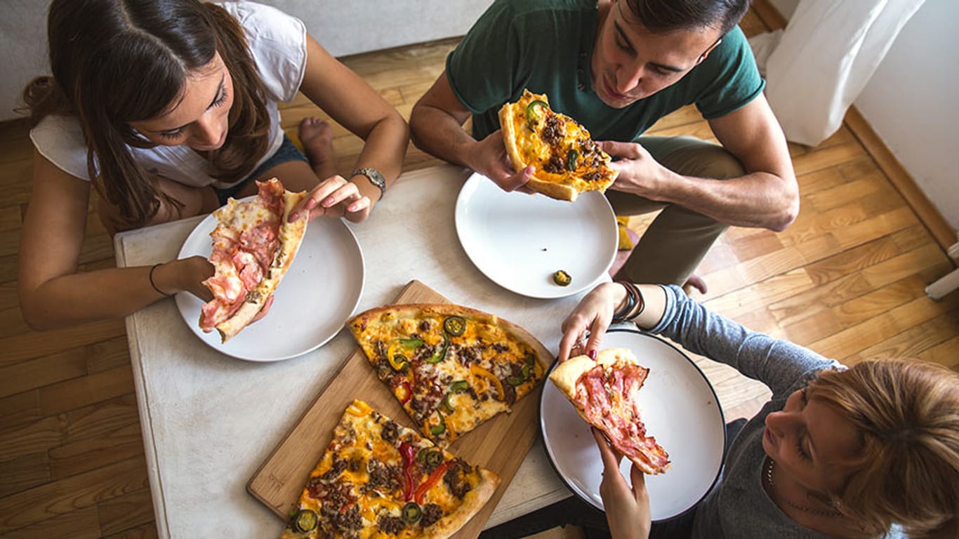 Menschen beim Pizzaessen: Laut WHO-Report ist in Europa die Anzahl übergewichtiger Menschen von 2010 bis 2014 gestiegen.