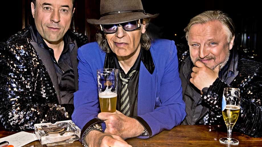 Glitzeranzug trifft Nuschelstimme: Jan Josef Liefers, Udo Lindenberg und Axel Prahl in "Soundtrack Deutschland". Glitzeranzug trifft Nuschelstimme: Jan Josef Liefers, Udo Lindenberg und Axel Prahl in "Soundtrack Deutschland".