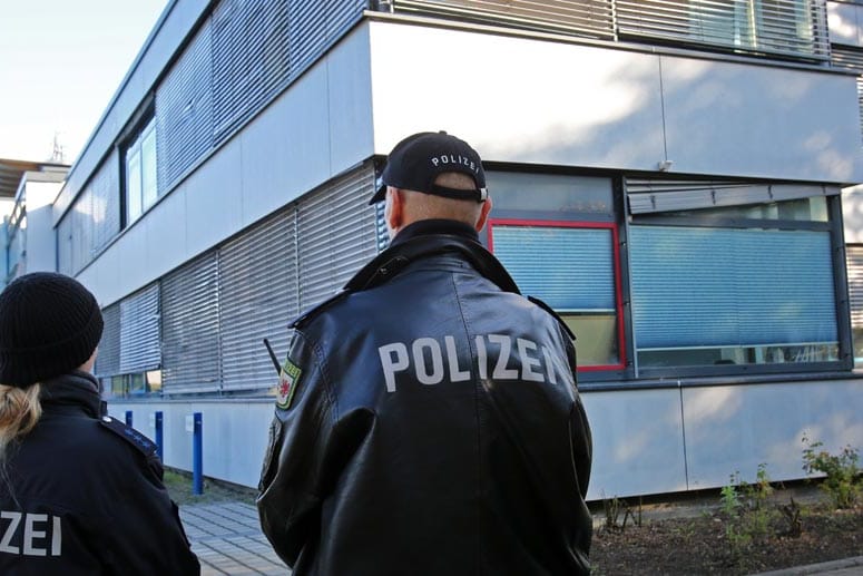 Polizisten stehen vor der verschlossenen Geschäftsstelle des FC Hansa Rostock Wache.