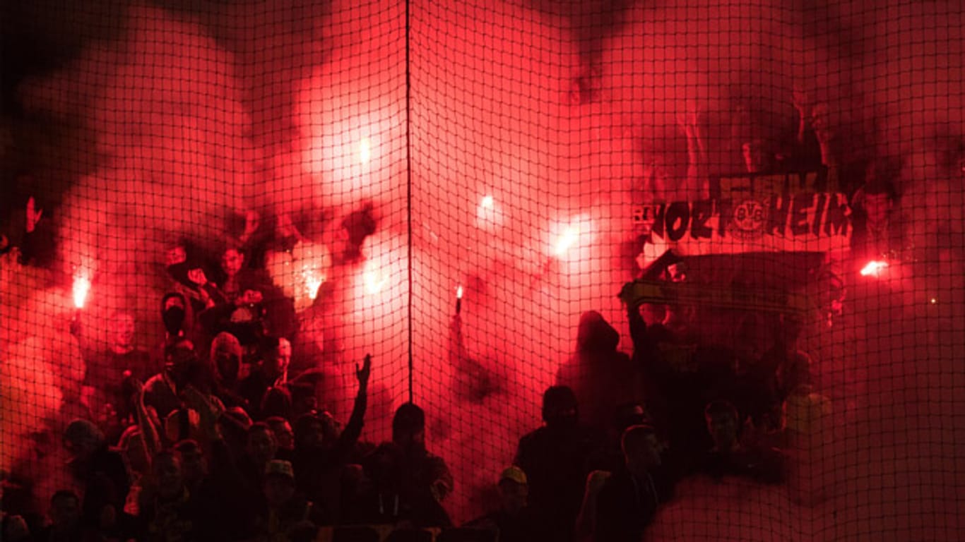 Die Dortmund-Anhänger tauchen den Gästeblock mit bengalischen Feuern in dunkelrot ein.