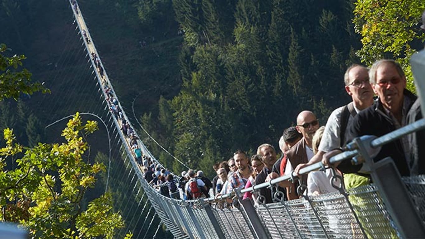 Die ersten Besucher gehen über die Geierlay Hängeseilbrücke.