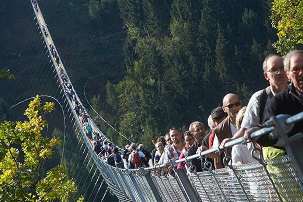 Die ersten Besucher gehen über die Geierlay Hängeseilbrücke.