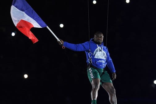 Schalke-Legende Gerald Asamoah wird mit wehender Frankreich-Fahne ins Stadion an Kabeln herabgelassen.