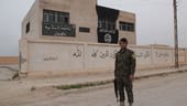 Ein kurdischer YPG-Kämpfer steht vor dem verwaisten Hauptquartier des IS in Al-Hawl.