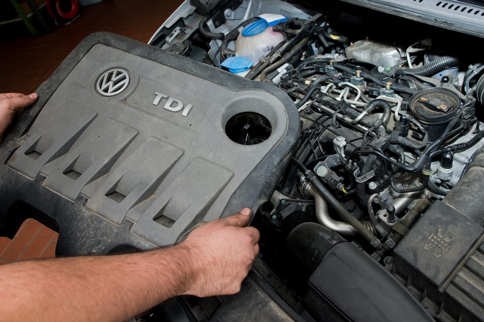 Ein KFZ-Mechaniker nimmt die Abdeckung vor einem VW-Dieselmotor Typ EA189.