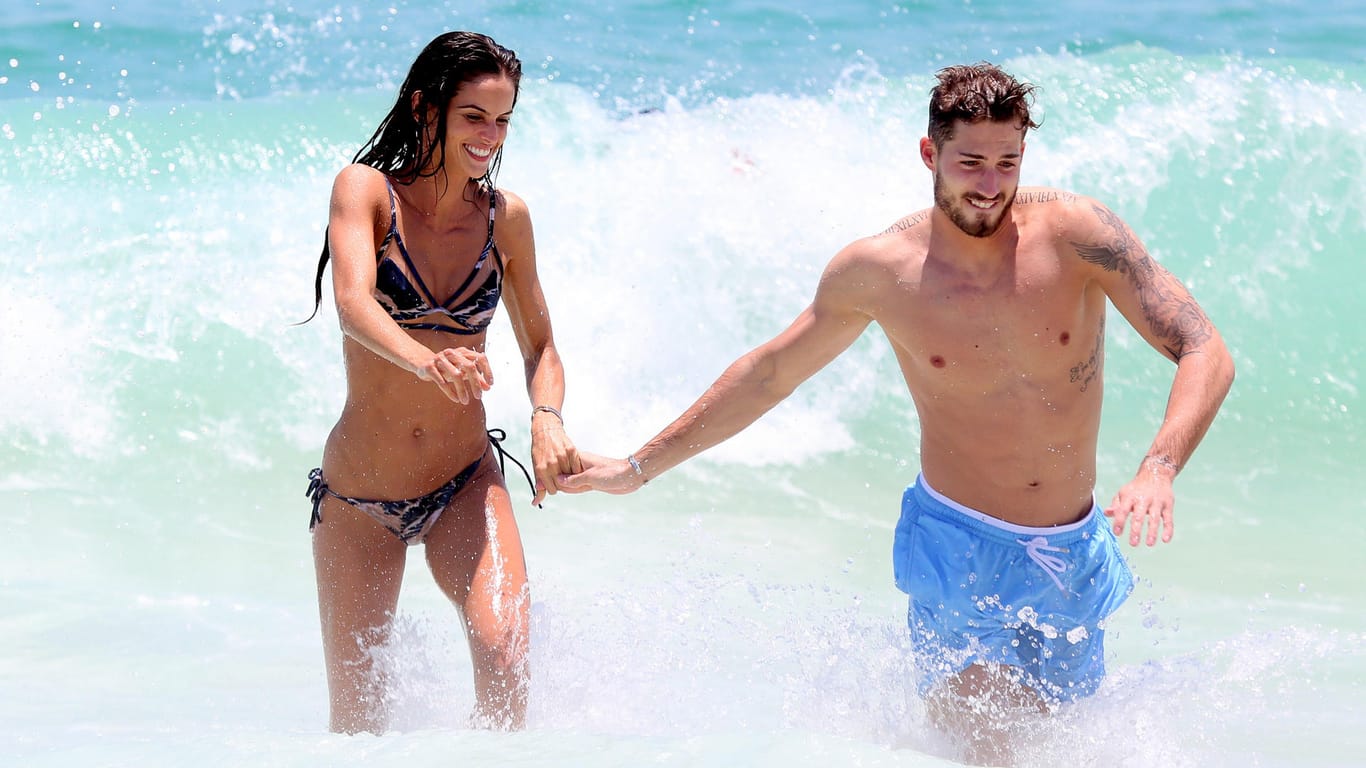 Liebesurlaub am Strand von Rio de Janeiro: Händchenhaltend stürzen sich Izabel Goulart und Kevin Trapp gemeinsam in die Wellen.