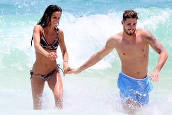 Liebesurlaub am Strand von Rio de Janeiro: Händchenhaltend stürzen sich Izabel Goulart und Kevin Trapp gemeinsam in die Wellen.