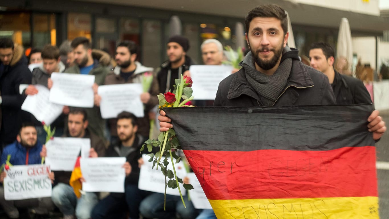 "Syrer gegen Sexismus" hat der 21-jährige Omar Kalawai auf seine Deutschlandflagge geschrieben. Gemeinsam mit anderen Flüchtlingen verteilte er in Würzburg Blumen vor allem an weibliche Passanten.