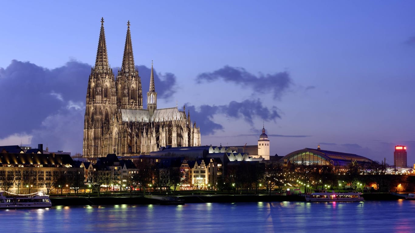 Mitten in Köln erhebt sich der Dom bei abendlicher Kulisse.