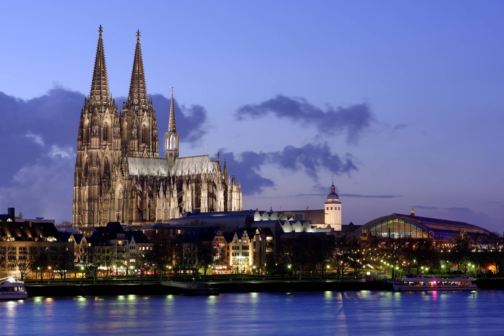 Mitten in Köln erhebt sich der Dom bei abendlicher Kulisse.