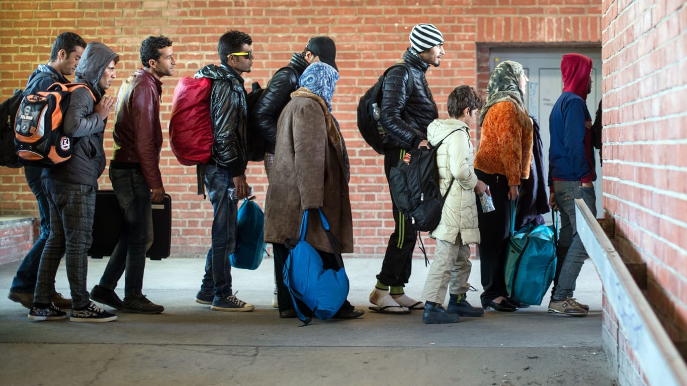 Migranten warten am Bahnhof in Schönefeld (Brandenburg) auf ihre Weiterfahrt zur Unterkunft mit Bussen.