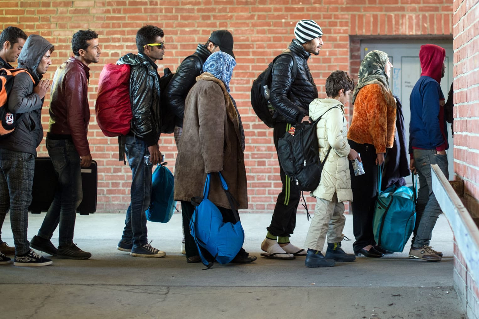 Migranten warten am Bahnhof in Schönefeld (Brandenburg) auf ihre Weiterfahrt zur Unterkunft mit Bussen.