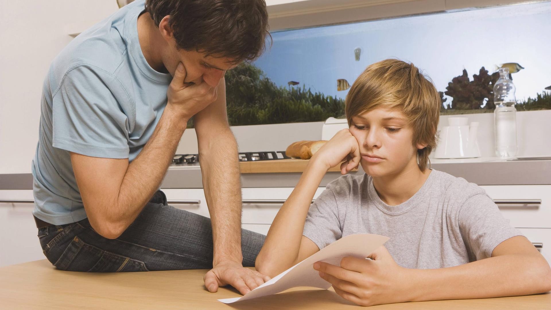 Ein Schüler zeigt seinem Vater sein Zeugnis: Ein schlechtes Schulzeugnis kann für viel Stress in der Familie sorgen.