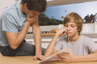 Ein Schüler zeigt seinem Vater sein Zeugnis: Ein schlechtes Schulzeugnis kann für viel Stress in der Familie sorgen.