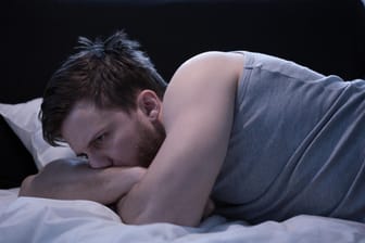 Frustrierter Mann liegt im Bett.