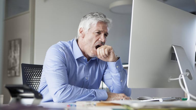 Müder Mann vor Monitor (Symbolbild): Der Chef darf den Arbeitnehmer zum Überstundenabbau früher nach Hause schicken.