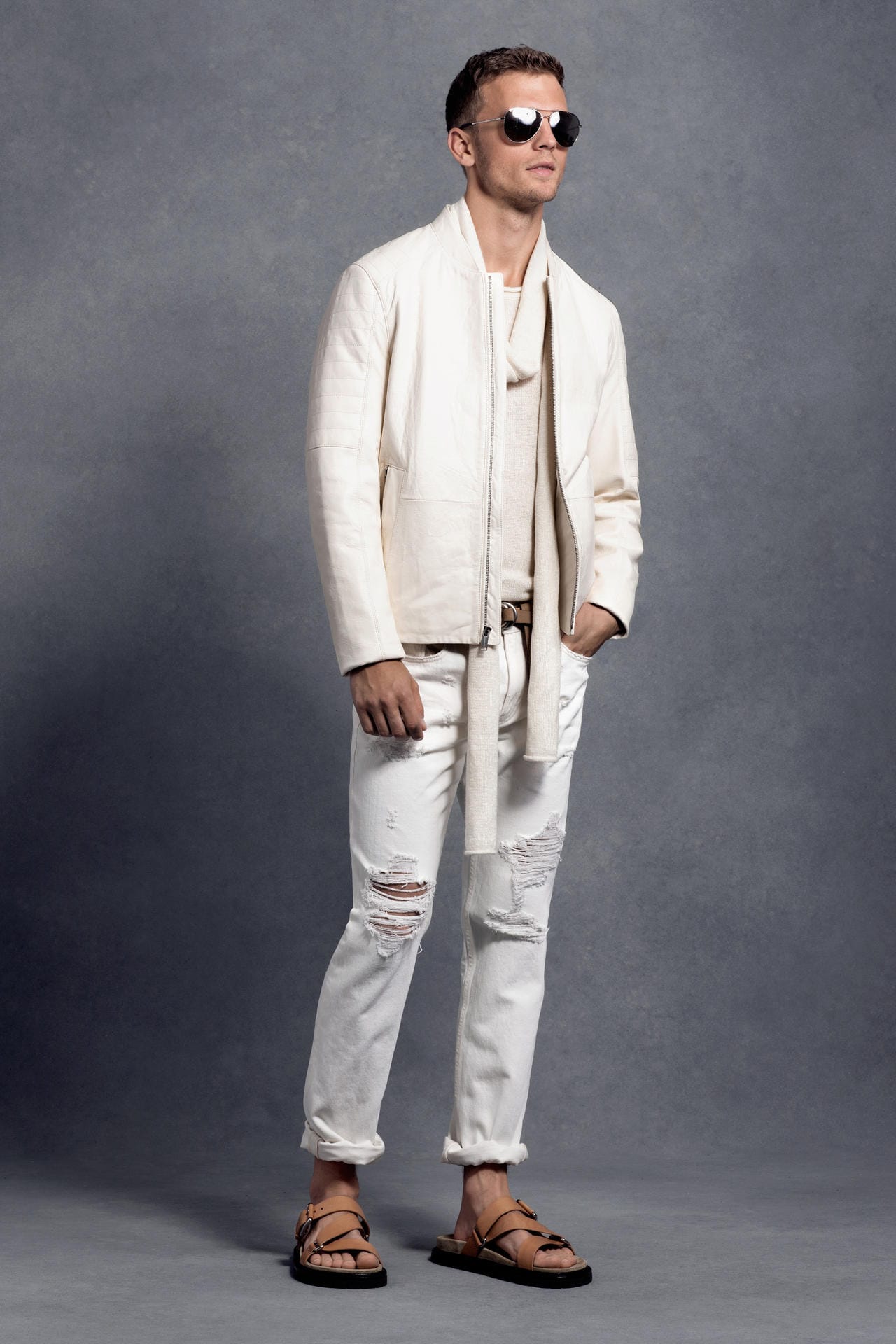Michael Kors zeigt weiße Destroyed Jeans zu Sandalen - im Sommer dürfen Männer gerne wild kombinieren (Lederjacke 1150 Euro, Pullover 260 Euro, Schal 170 Euro, Jeans 170 Euro, Sandalen 200 Euro).