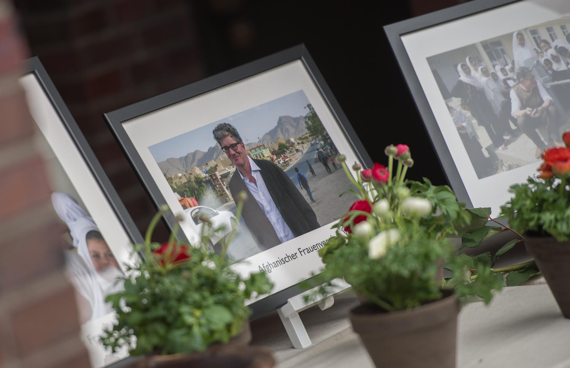 Bilder vom Afghanischen Frauenverein e.V., dessen Schirmherr Roger Willemsen war, stehen zwischen den Blumen.