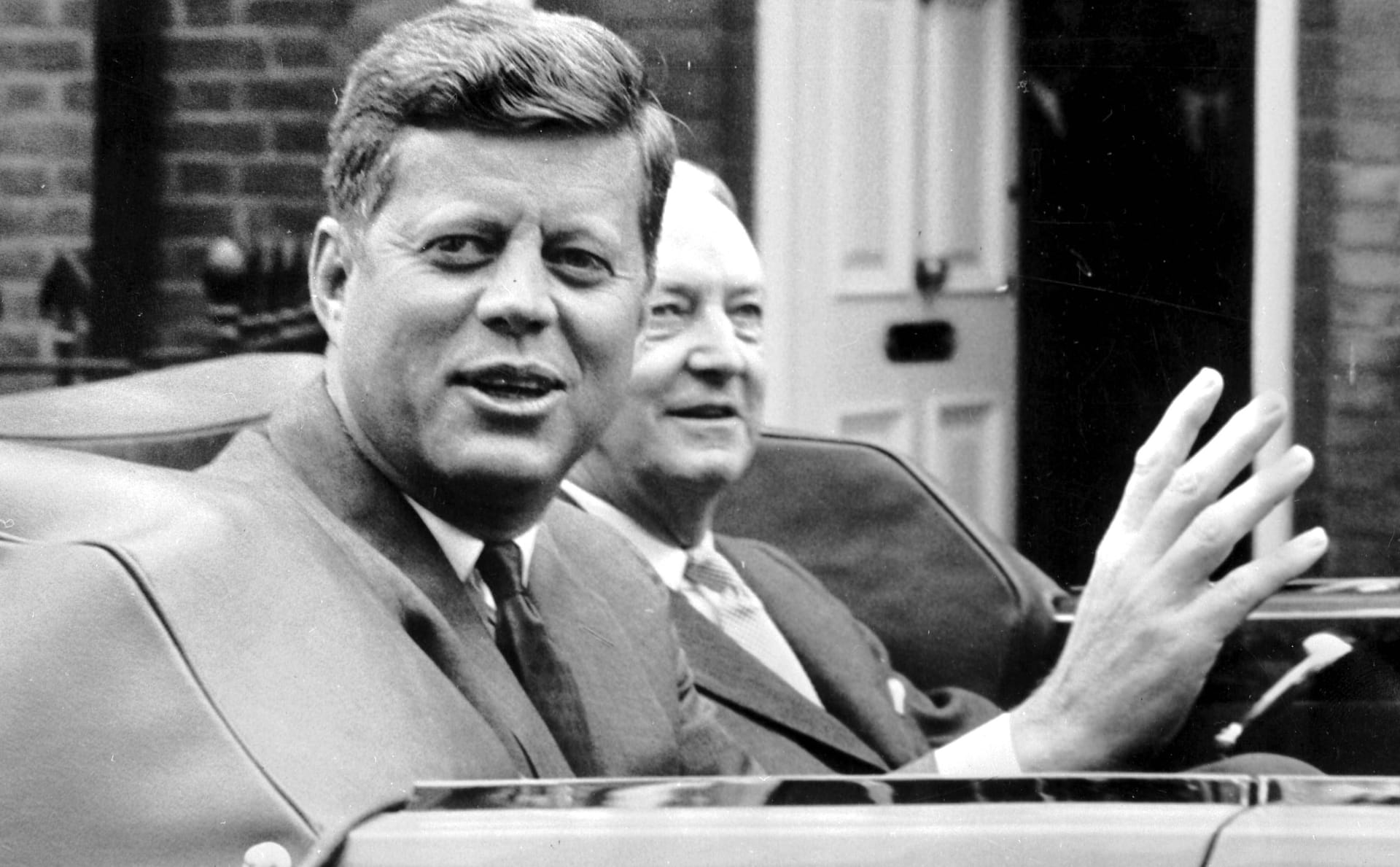 John F. Kennedy in einem offenen Wagen.
