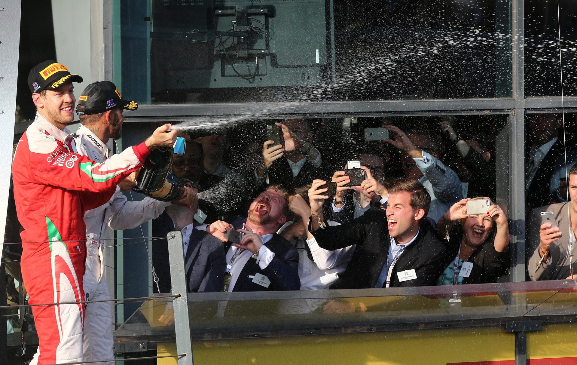 Sebastian Vettel (vorne) und Lewis Hamilton versprüchen Champagner auf dem Podium - zur Freude der VIP-Fans.