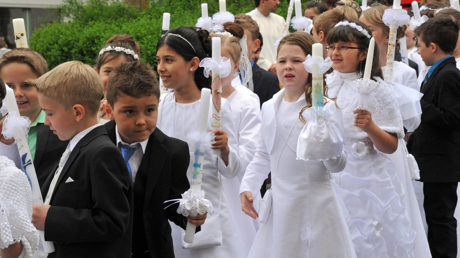 Nach dem Gottesdienst folgt die Prozession aus der Kirche mit Kommunionskerze.