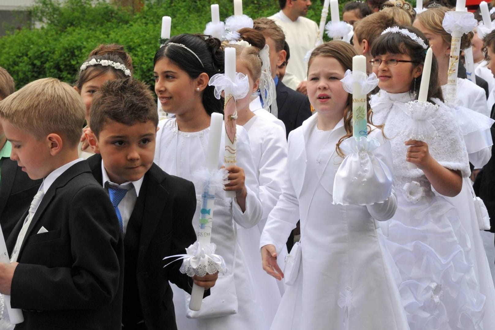 Nach dem Gottesdienst folgt die Prozession aus der Kirche mit Kommunionskerze.