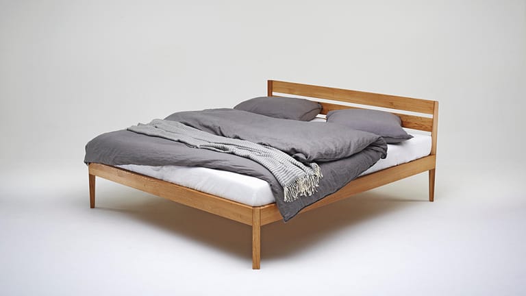 Bleibt der sichtbare Boden unter dem Bett frei, wirkt auch ein kleines Schlafzimmer mit solch einem filigranen Massivholzbett luftig.