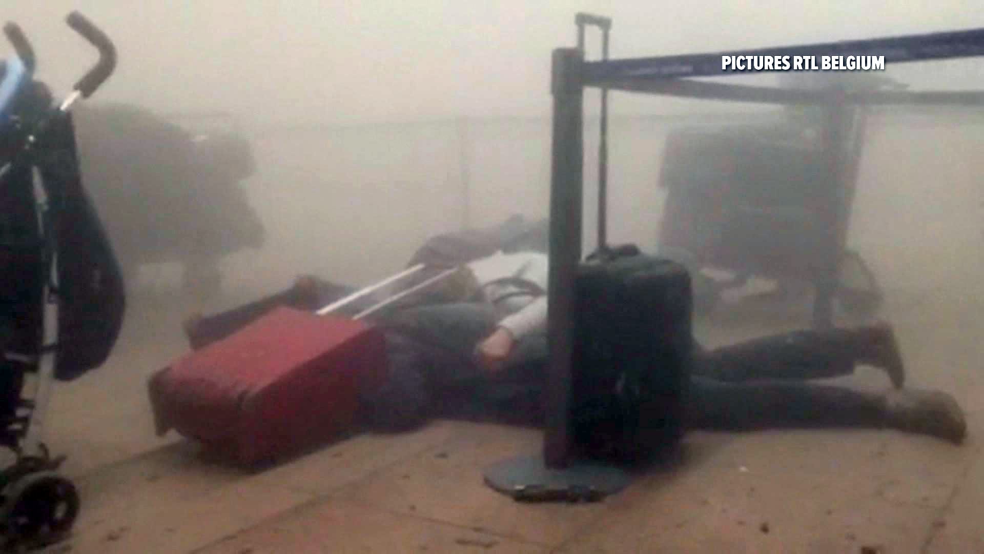 Eine Standbildaufnahme von RTL Belgien zeigt zwei Reisende, die nach der Detonation am Flughafen auf dem Boden liegen.
