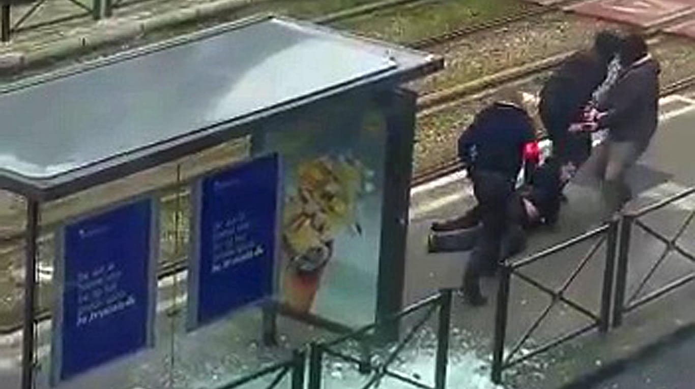 Belgische Polizisten bringen einen Verdächtigen an einer Straßenbahnhaltestelle zu Boden.